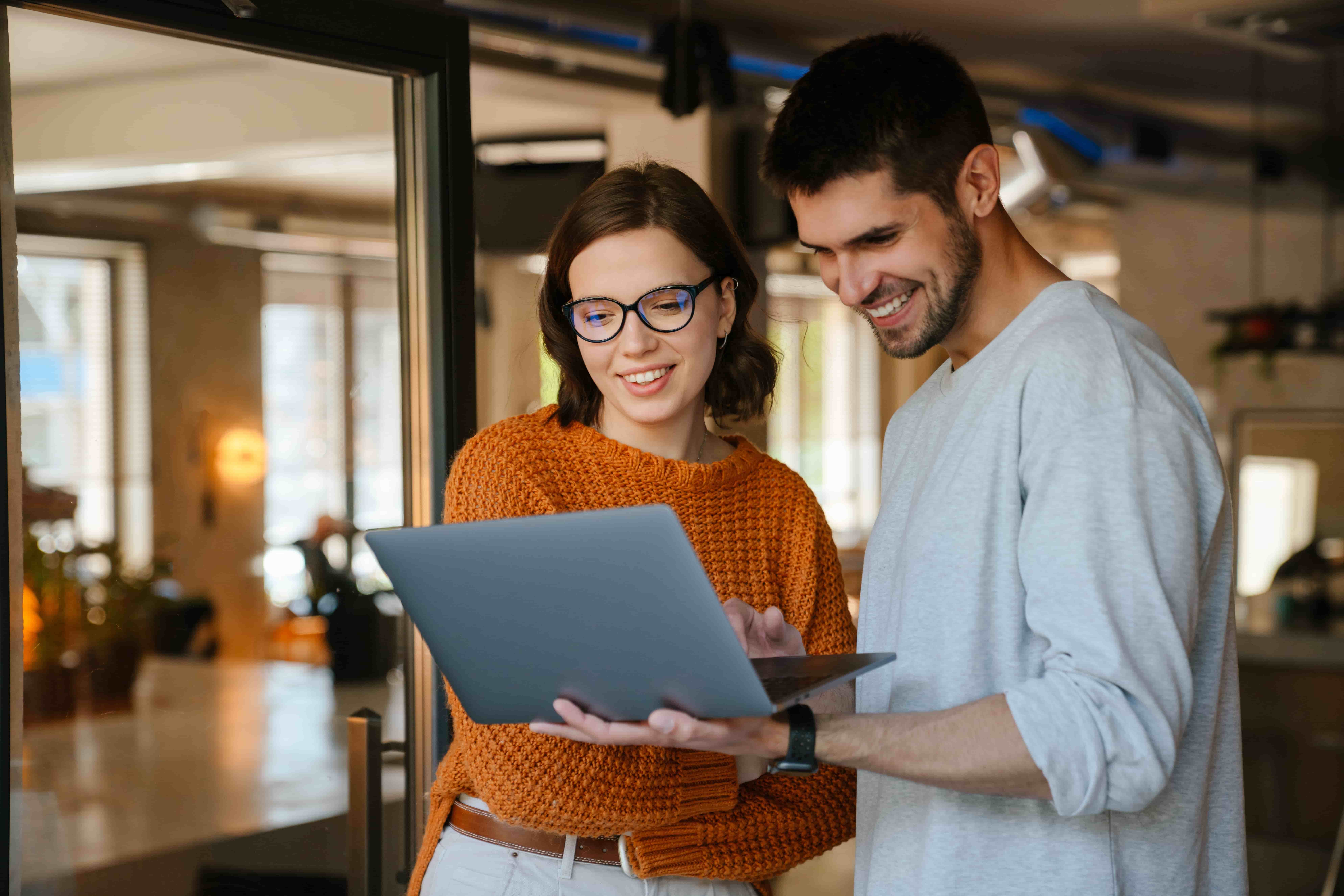 White colleagues discussing project while working with laptop in office indoors